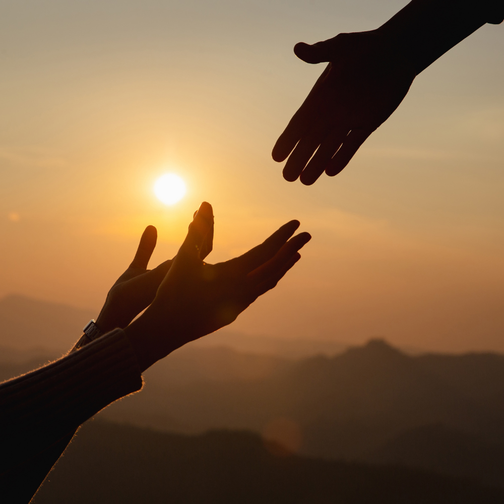 silhouette of helping hands at sunset